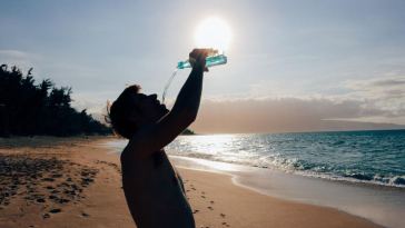 man on beach drinking water