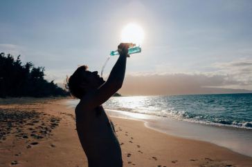 man on beach drinking water