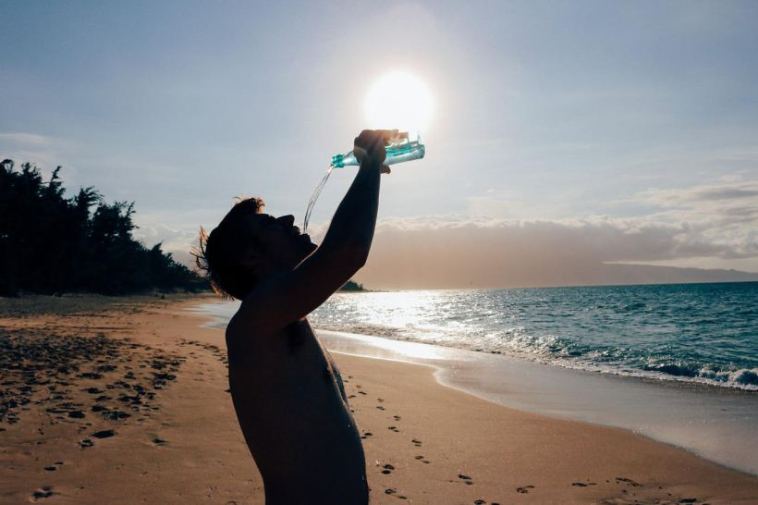 man on beach drinking water
